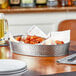 A Tablecraft oval stainless steel platter with a plate of chicken wings on a table.