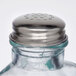 A close-up of a Tablecraft green tint glass salt shaker with a silver lid.