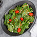 A Libbey Driftstone Onyx Satin Matte porcelain coupe plate with spinach salad, tomatoes, and feta cheese.