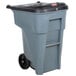 A Rubbermaid grey rectangular trash can with wheels and locking lid.