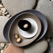 A Libbey Driftstone porcelain bowl with a piece of chocolate on it sitting on a rock.