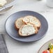 A Libbey Driftstone granite satin matte porcelain coupe plate with bread and butter on it.