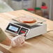 A digital portion control scale with a display showing the weight of sliced meat on a sheet of paper.