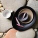 A white Libbey porcelain cup on a stone surface with a bowl of fruit slices.