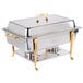 A Vollrath stainless steel chafing dish with brass trim on a table outdoors.