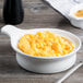 A Libbey white porcelain casserole dish filled with macaroni and cheese on a table next to a fork.