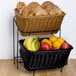 A black metal stand with a basket of bread and fruits on top.