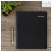 An At-A-Glance black spiral bound monthly planner on a wood surface.