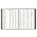 A close-up of a black spiral bound At-A-Glance monthly planner with white pages.