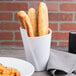 A white Elite Global Solutions small spiral crock filled with bread on a table next to a plate of food.
