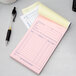 An Adams blue and white sales order pad on a counter with a pen and a cup of coffee.