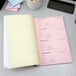 A close up of an Adams 3-part carbonless receipt book with a pen on a desk.