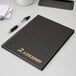 A black Adams two column account book with a pen.