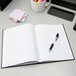 An Adams black notebook with a pen on it.