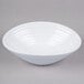 A white oblong melamine bowl with a circular design on a gray surface.