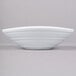 A white oblong Elite Global Solutions melamine bowl with a white swirl design on a gray surface.