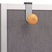 A grey board with a metallic grey Alba cubicle garment peg on it.
