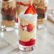 Three Acopa Straight Up juice glasses filled with dessert and topped with whipped cream.