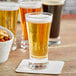 A table with a variety of Acopa Pilsner beer glasses filled with beer.