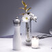 A white Chef Specialties pepper mill on a table with flowers and a candle.
