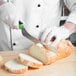 A person cutting bread with a Mercer Culinary Millennia Colors bread knife.