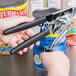 A person using a Garde handheld crank can opener to open a can on a counter.