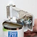 A person using a Choice wall mount can opener to open a metal bracket on a can.