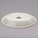 A white Tuxton oval china platter with a black rim.
