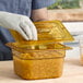 A person wearing gloves and holding a plastic container with food.