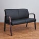 A black leather loveseat with wooden legs.