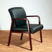 A black leather Alera reception arm chair with mahogany wood legs.