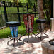 A metal table with a black top and two Holland Bar Stool United States Army LED bar stools on an outdoor patio.