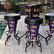 A round metal table with a Louisiana State University LED bar stool and a purple and yellow bucket on it.