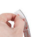 A hand holding a plastic-wrapped roll of 3M Scotch Black Extreme Fastener tape.