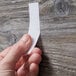 A person holding a white strip of 3M Scotch multi-purpose fastener tape.