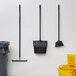 3M Command Clear Medium Wire Toggle Hooks holding brooms and buckets on a wall.