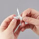 A person's hands using a 3M Command clear medium hook to hang a piece of paper.