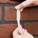 A person holding a white plastic strip with a close-up of a hand.