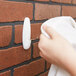 A hand hanging a white towel on a white 3M Command hook.