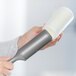A hand holding a white and grey 3M Scotch-Brite lint roller.