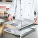 A person holding a Baker's Mark metal tray with extender and bun pan on it.