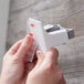 A person's hands holding a 3M clear mounting strip.