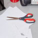 3M Scotch stainless steel pointed tip precision scissors with red and dark gray handles on a desk.