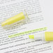 A yellow and white tube of 3M Post-It flag highlighter on a piece of paper.
