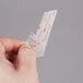 A person's hand using a white plastic Scotch clear fastener to attach a piece of paper.