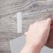 A hand uses a 3M clear fastener to attach a piece of wood.