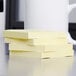 A stack of 3M Post-It fan-folded yellow sticky notes on a table.