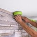 A man using 3M Scotch green masking tape to put a tape on a wall.