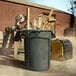 A grey Rubbermaid Brute plastic trash can filled with wood pieces.