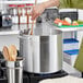 A person cooking food in a Choice aluminum stock pot on a stove.